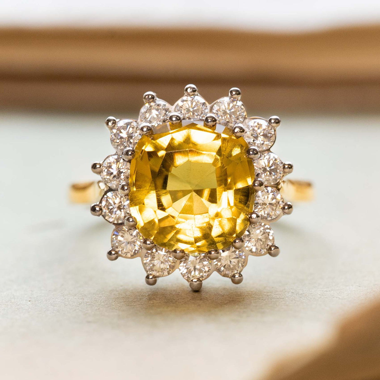 An antique-inspired, yellow sapphire and diamond cluster engagement ring set in white gold with a yellow gold band.