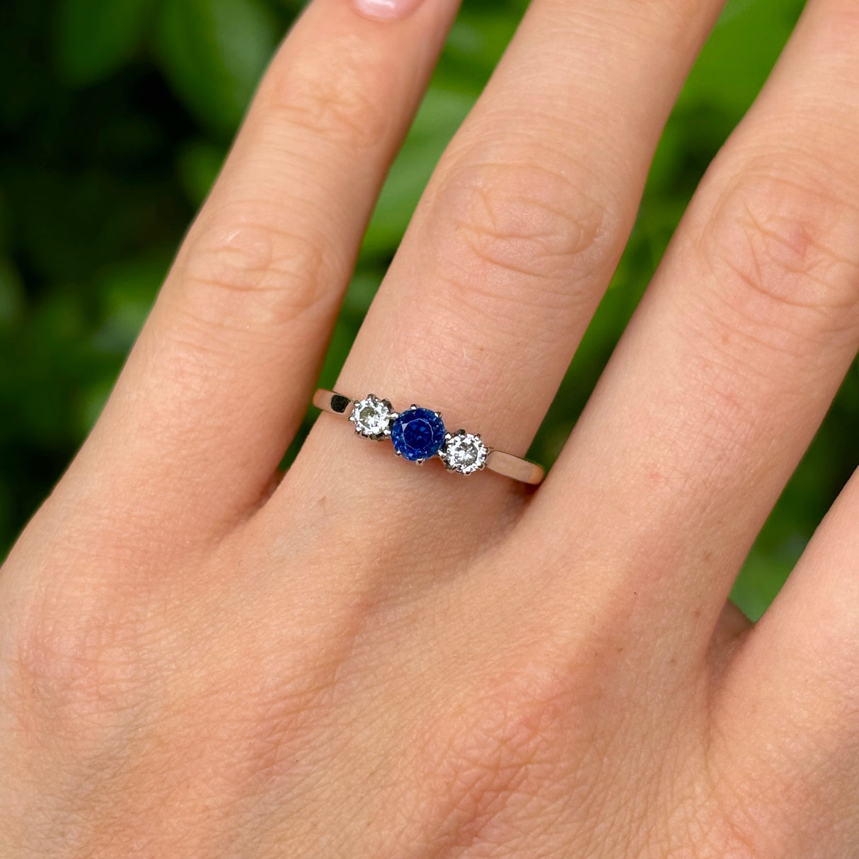 Antique, Edwardian sapphire and diamond three-stone ring worn on hand.