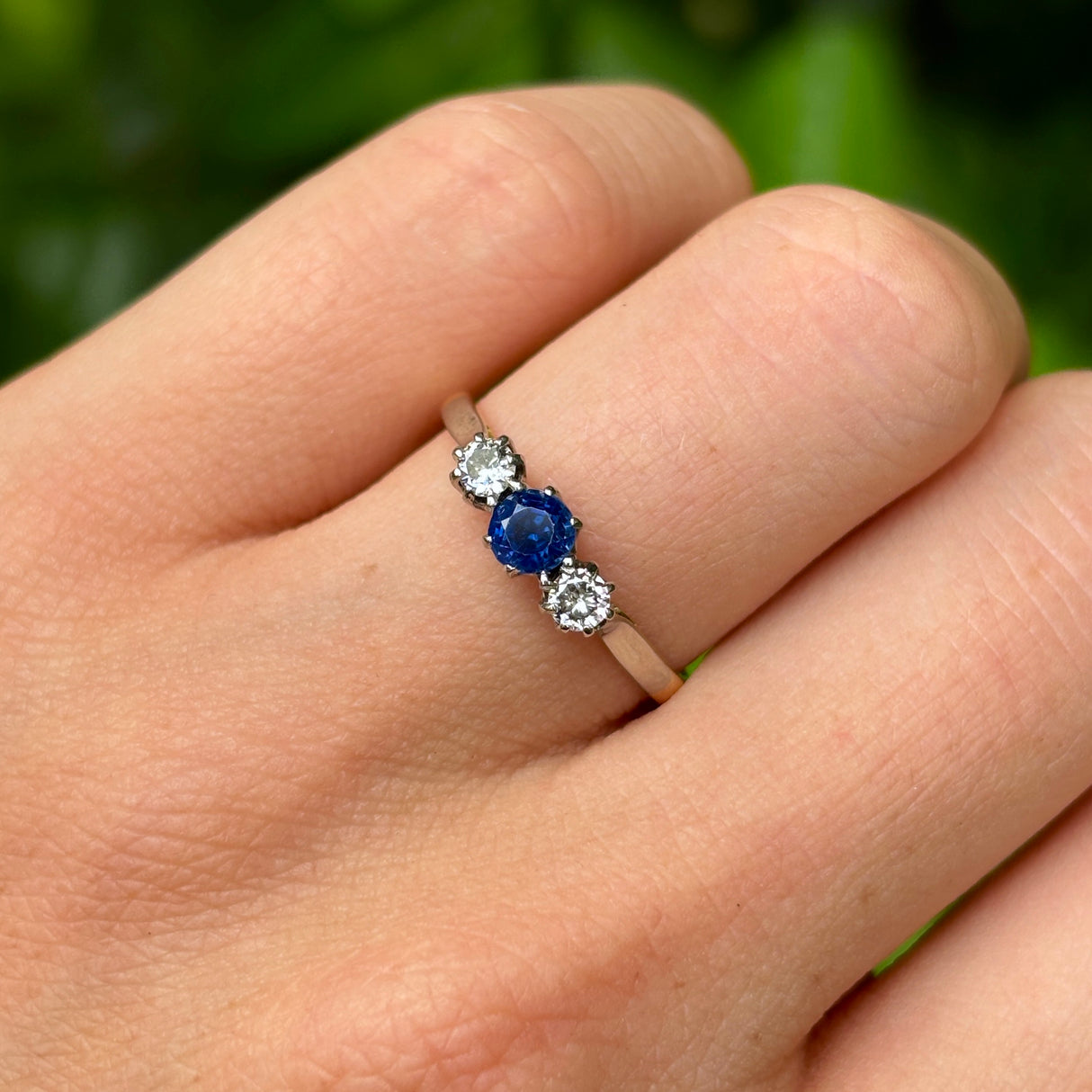 Antique, Edwardian sapphire and diamond three-stone ring worn on hand.