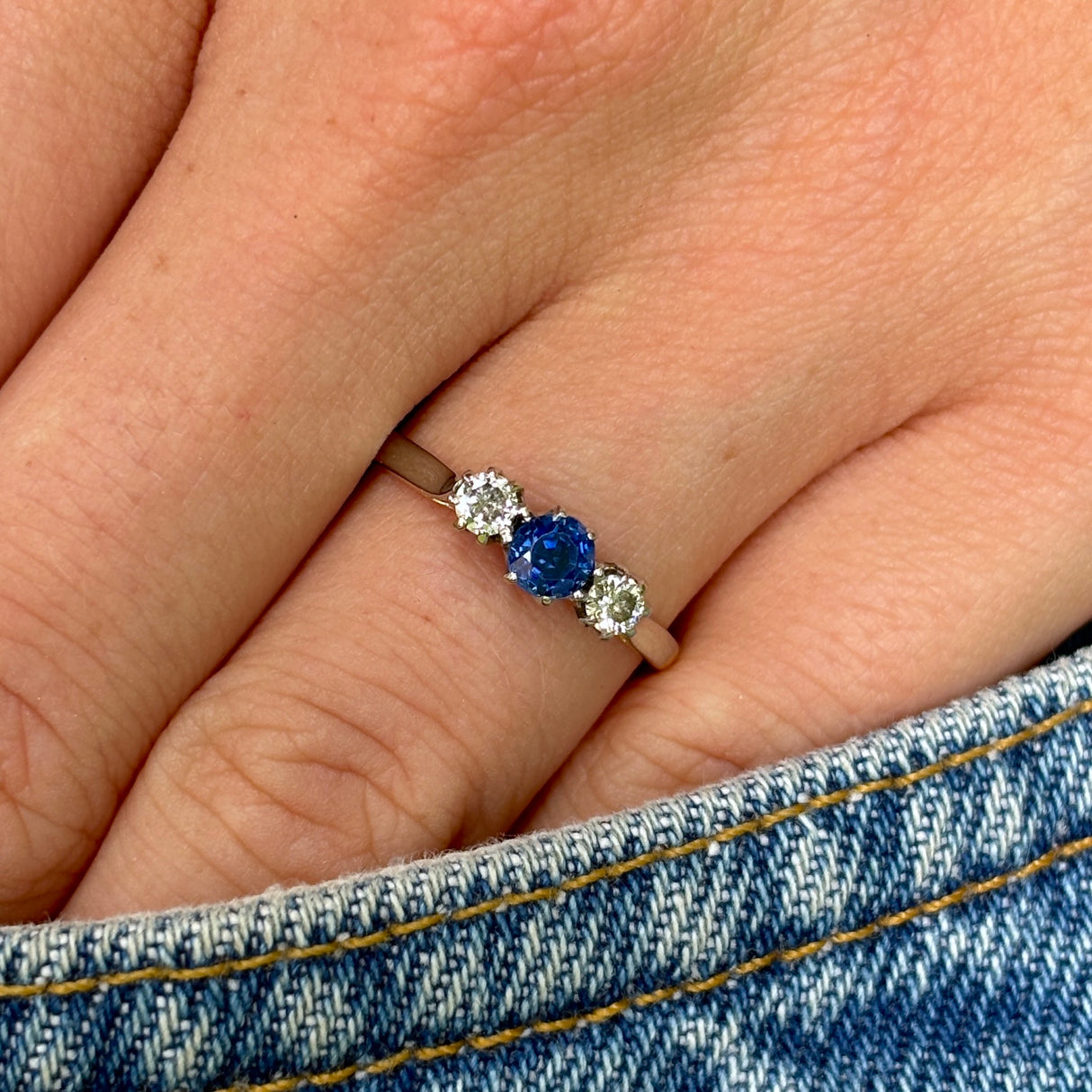 Antique, Edwardian sapphire and diamond three-stone ring worn on hand.