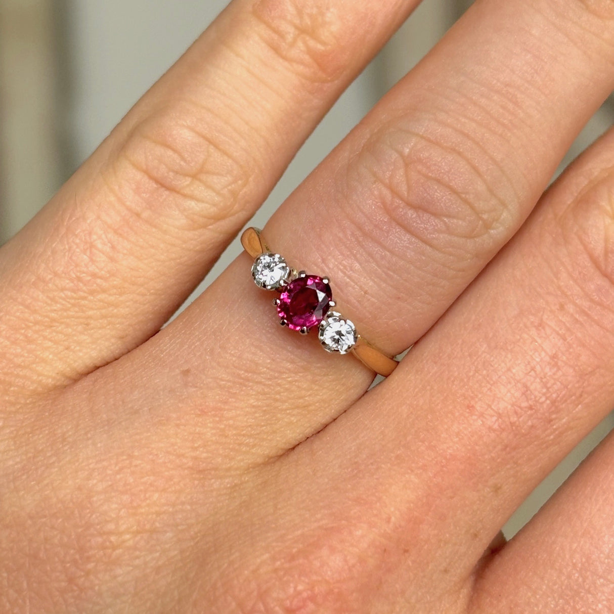 Antique, Edwardian ruby & diamond three-stone ring worn on hand.