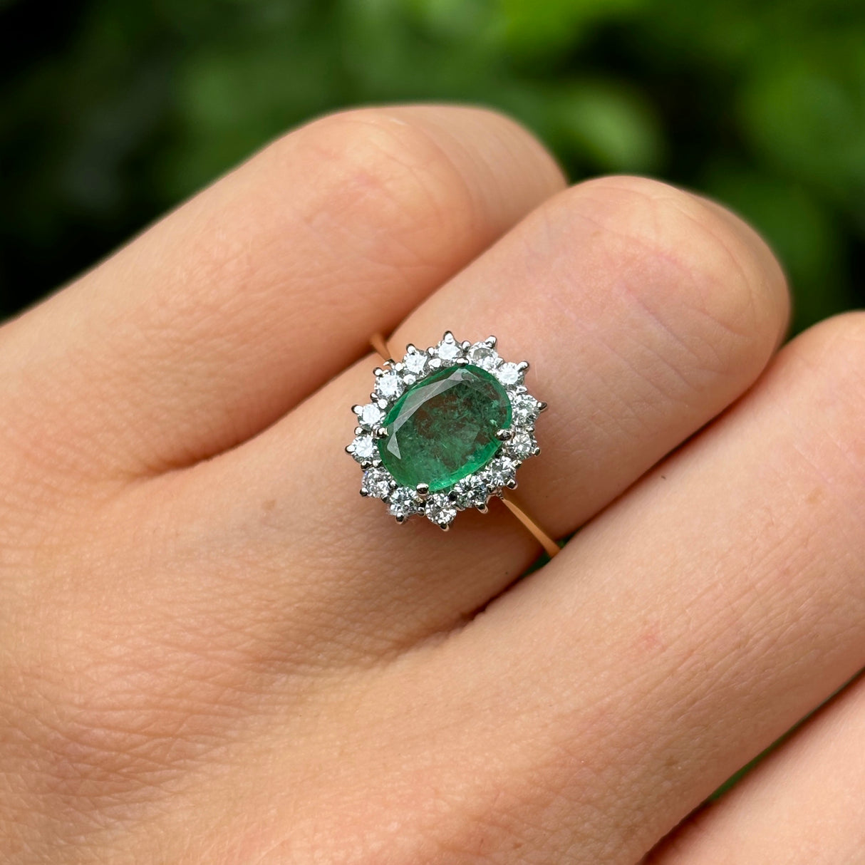 Vintage, 1990s emerald & diamond cluster ring worn on hand.