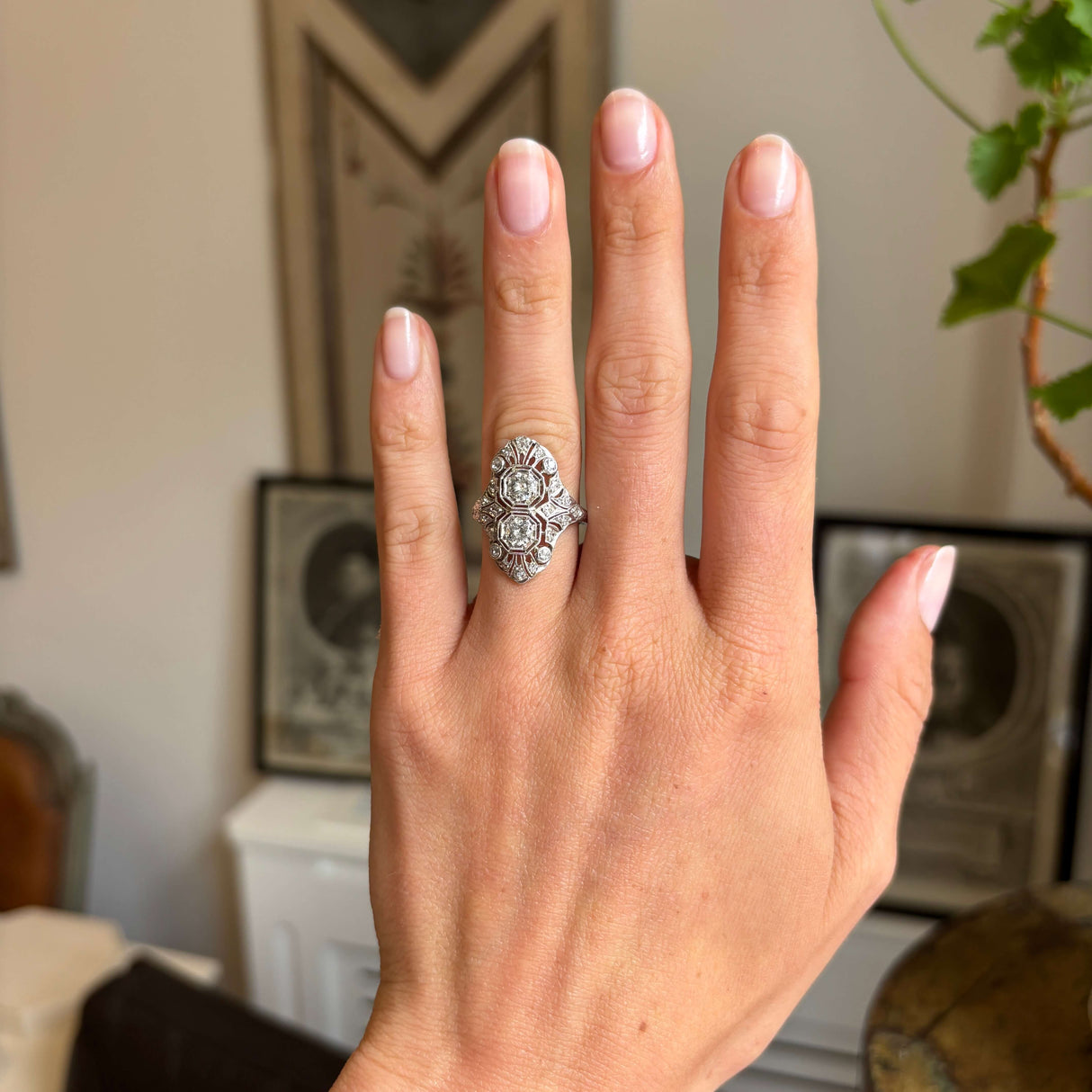 Antique 1920s platinum diamond cluster cocktail ring worn on hand, showcasing an ornate Art Deco filigree design with sparkling old-cut diamonds in natural light.