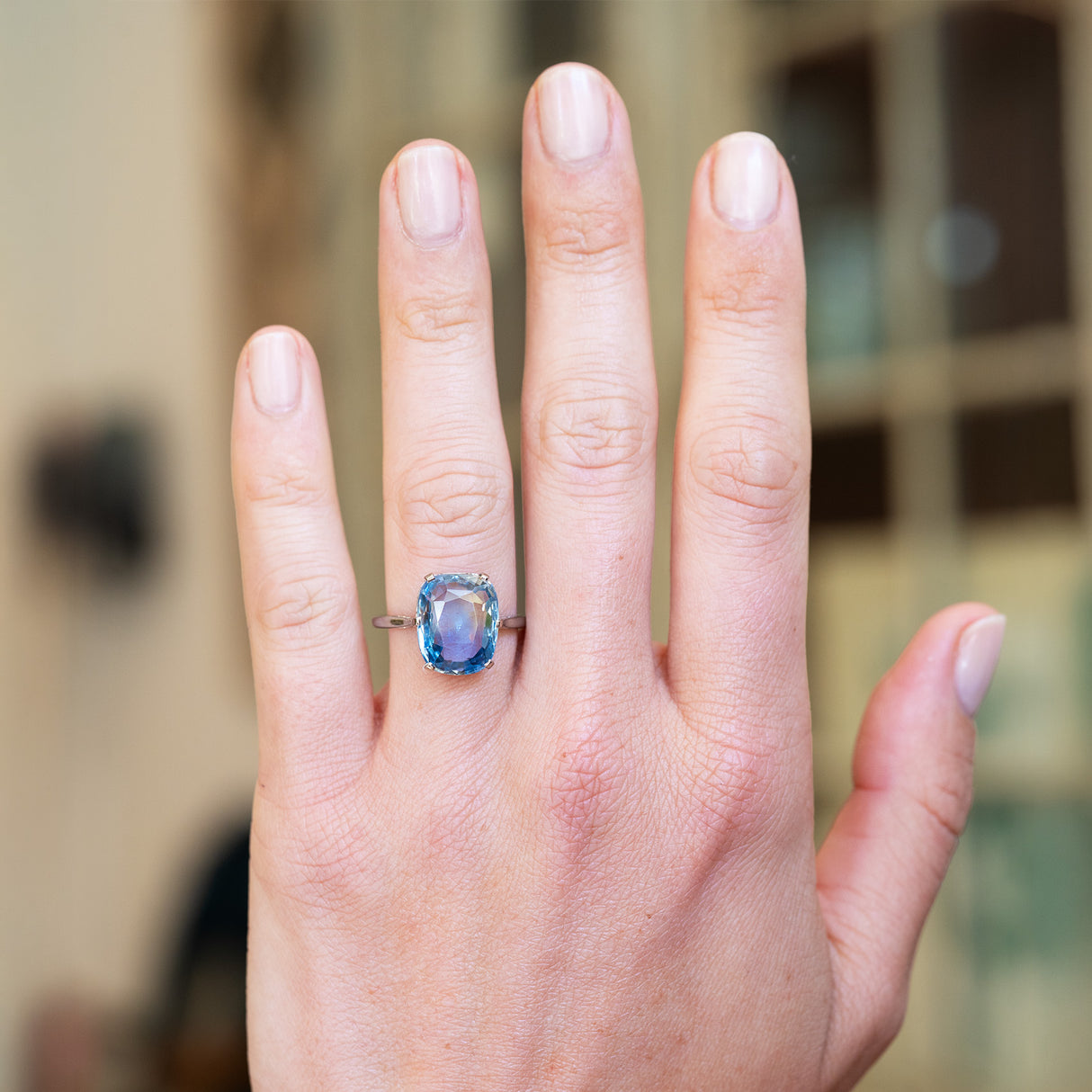 Pale blue sapphire solitaire ring worn on hand.