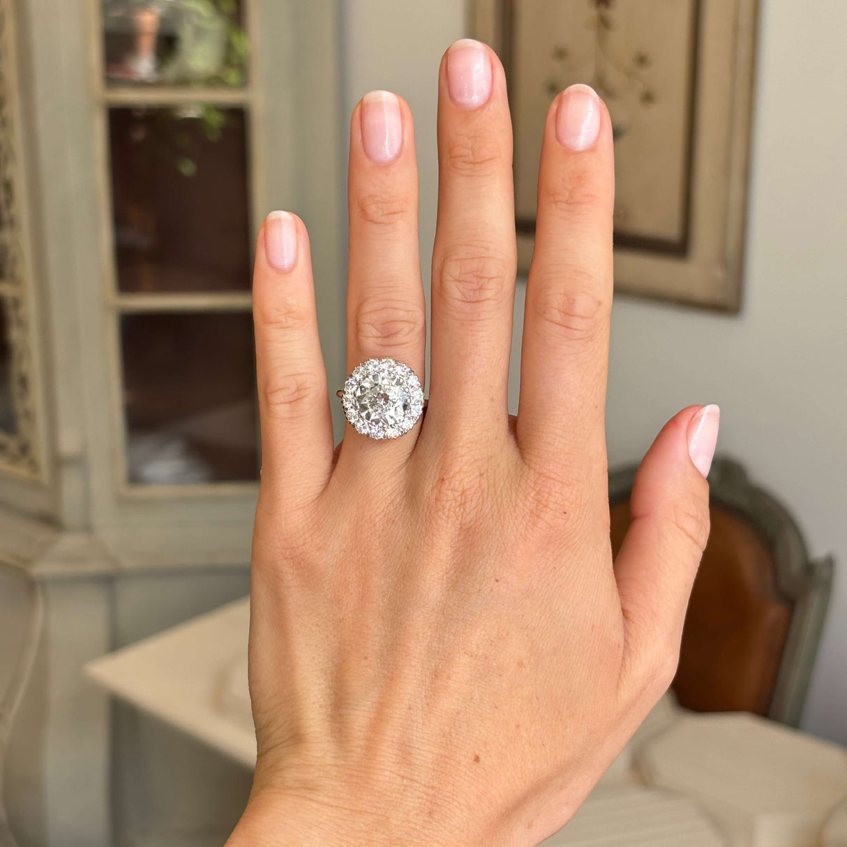 Vintage platinum diamond cluster ring worn on hand, showcasing a dazzling 1950s design with an impressive cluster of brilliant-cut diamonds and exceptional sparkle.