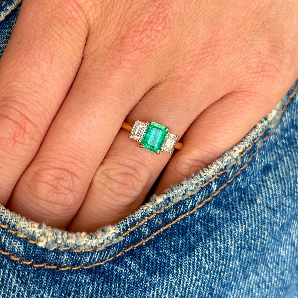 Vintage Emerald & diamond three-stone ring worn on hand.