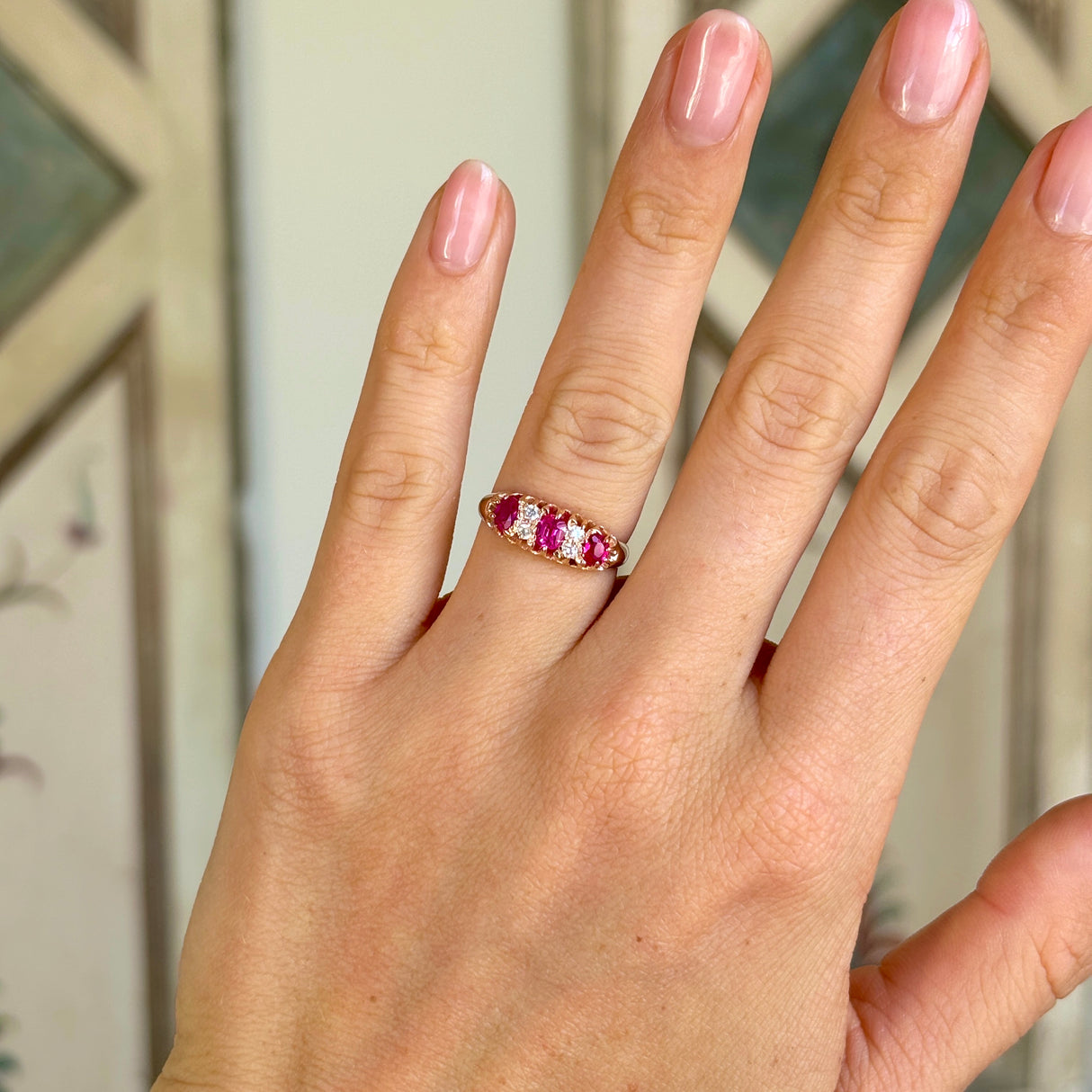 Antique, Victorian pinky-red ruby & diamond half-hoop ring worn on hand.