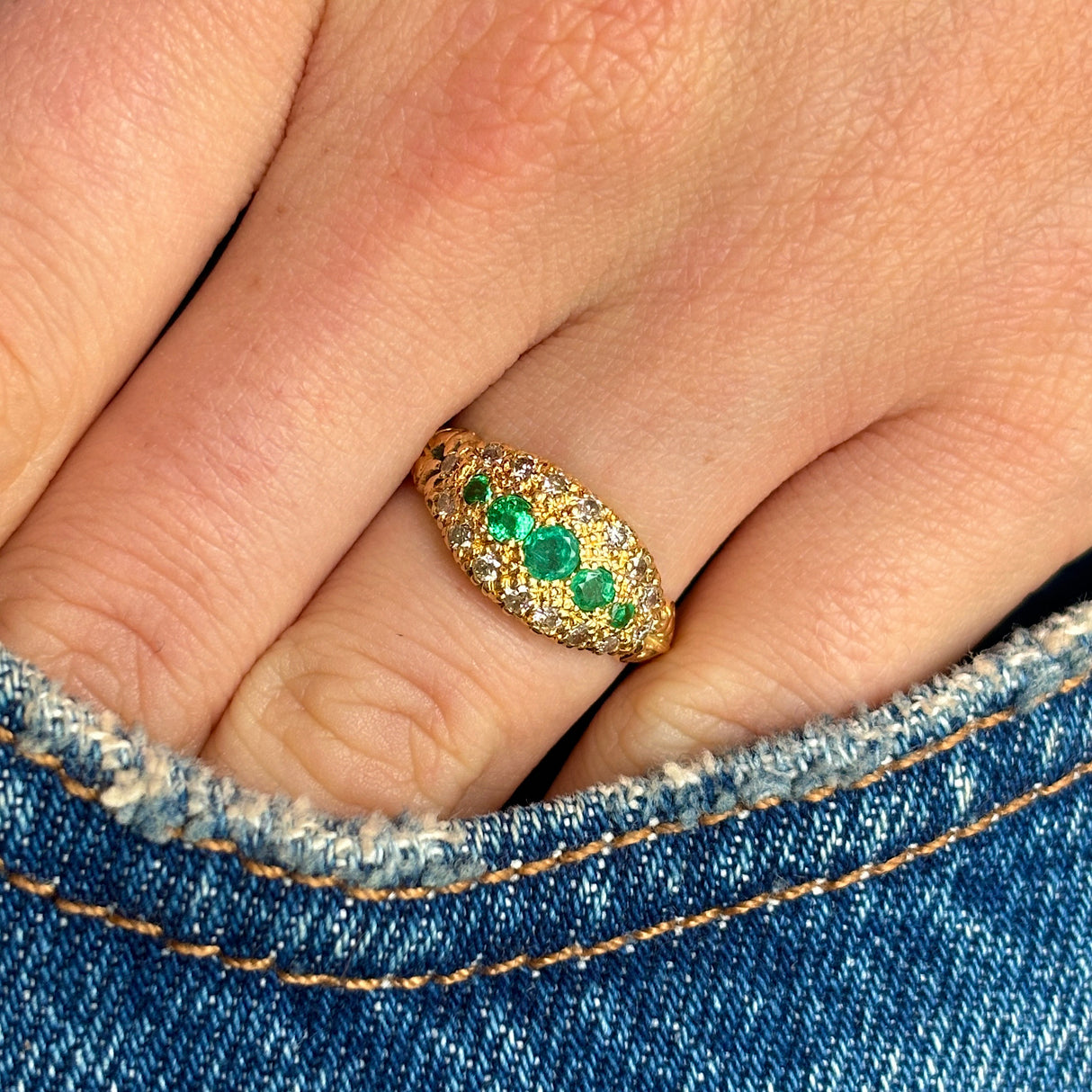 Vintage, 1970s emerald & diamond cluster ring worn on hand.