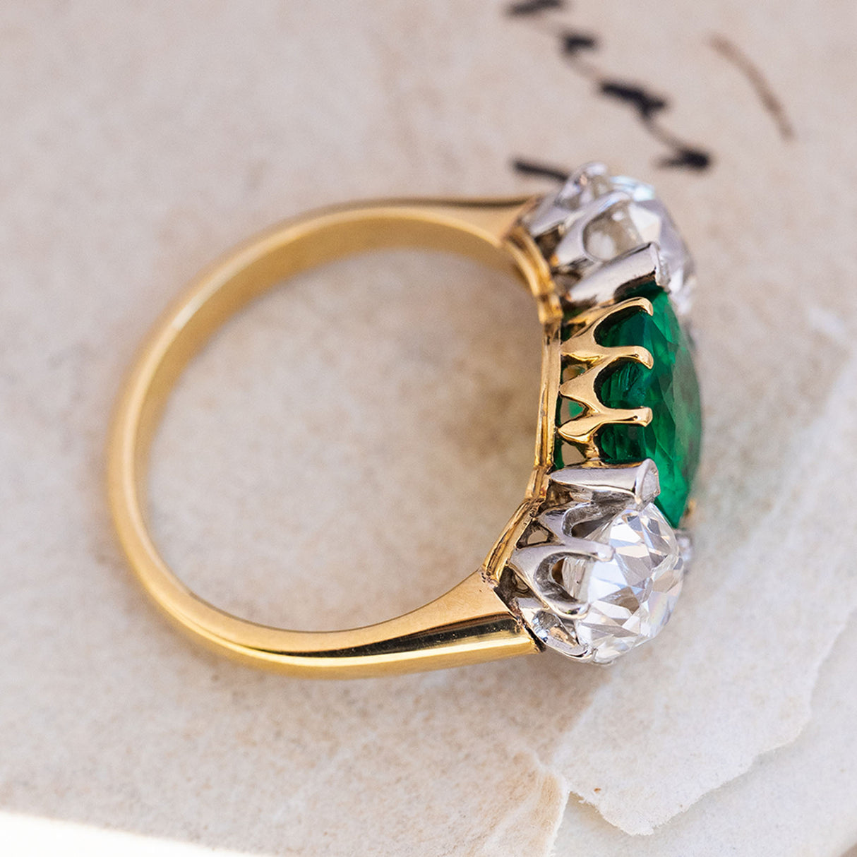 Gallery view of an antique Edwardian octagon-cut emerald and old-mine diamond three-stone engagement ring in yellow gold.