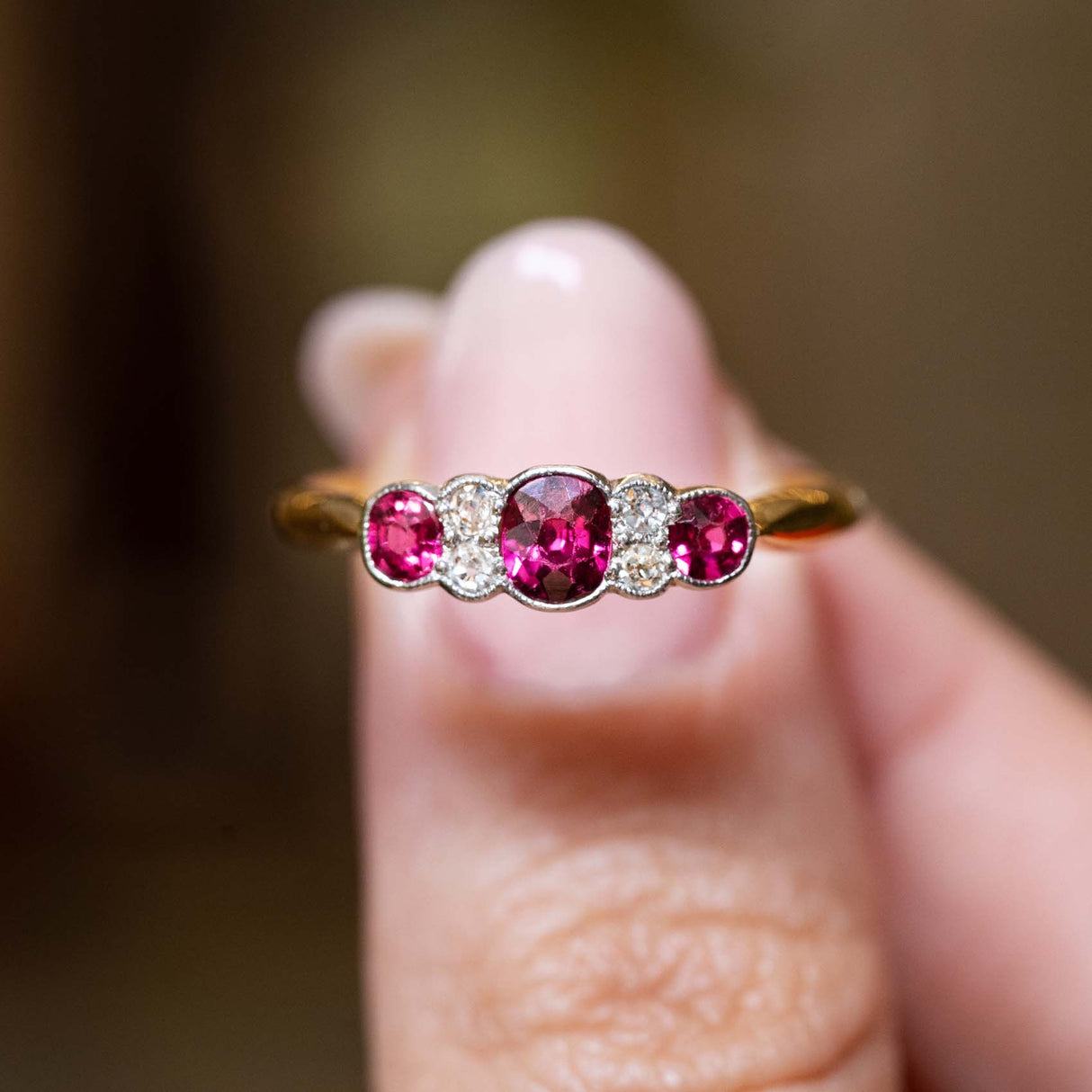 Close-up of an antique Edwardian five-stone ring featuring natural rubies and old-cut diamonds.