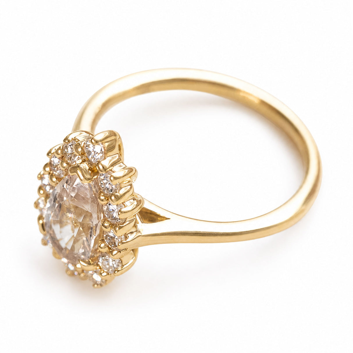 A gold ring with a pear-cut sapphire and a halo of round brilliant-cut diamonds.