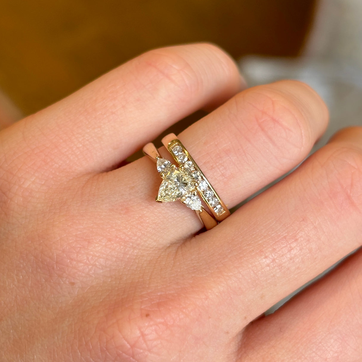 Ethical Pear-Cut Central Diamond With Pear-cut Diamond Shoulders Three-Stone Wed-Fit Engagement Ring View on Finger With Wedding Band