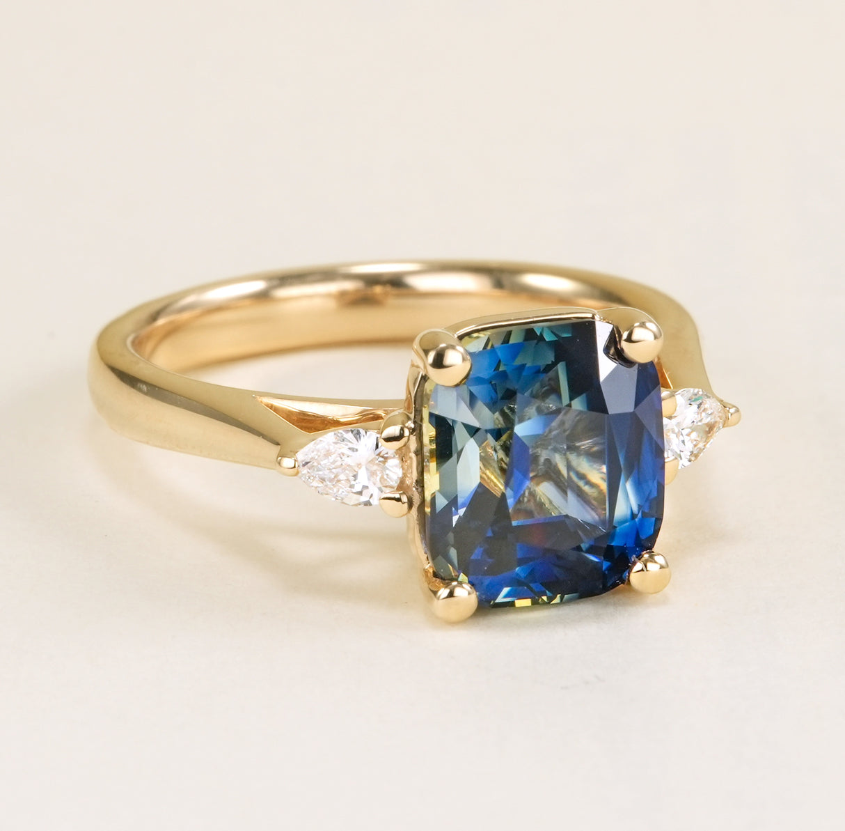 Colour-change cushion cut sapphire and diamond three-stone ring