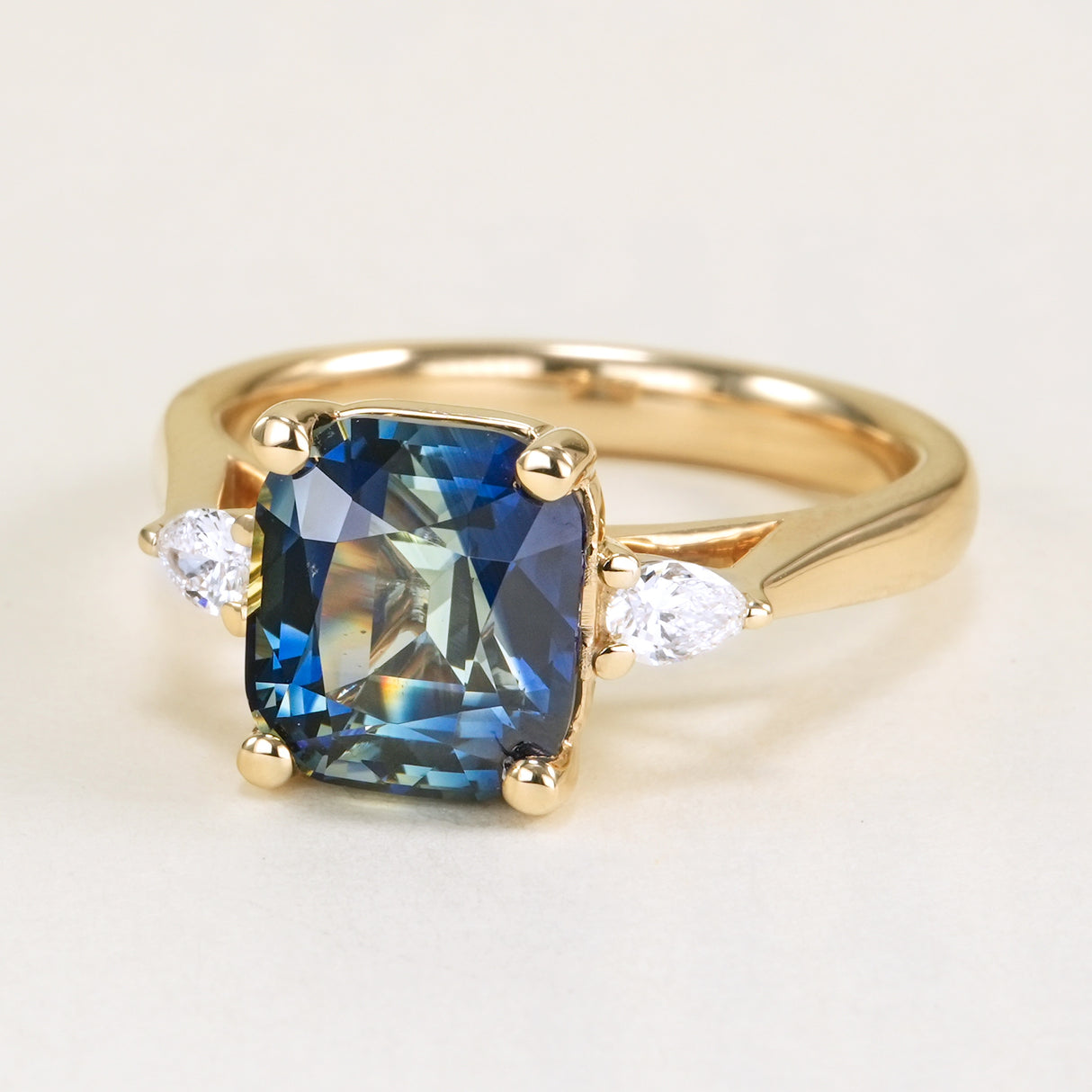 Colour-change cushion cut sapphire and diamond three-stone ring