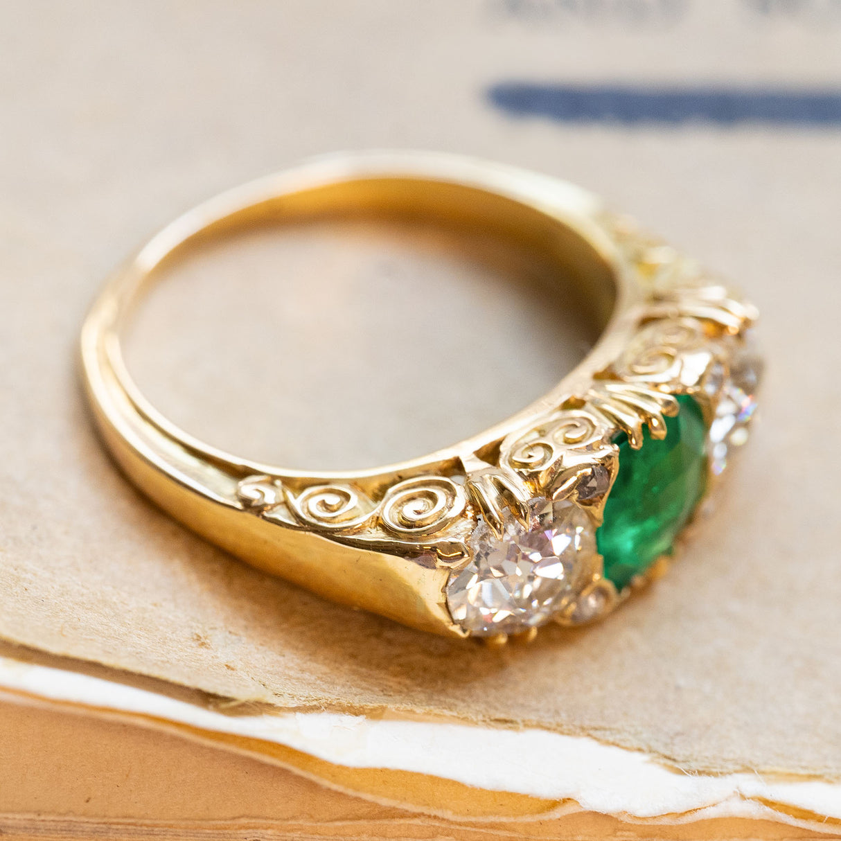 An antique Victorian Colombian emerald and old-cut diamond ring in 18ct yellow gold with an engraved design.