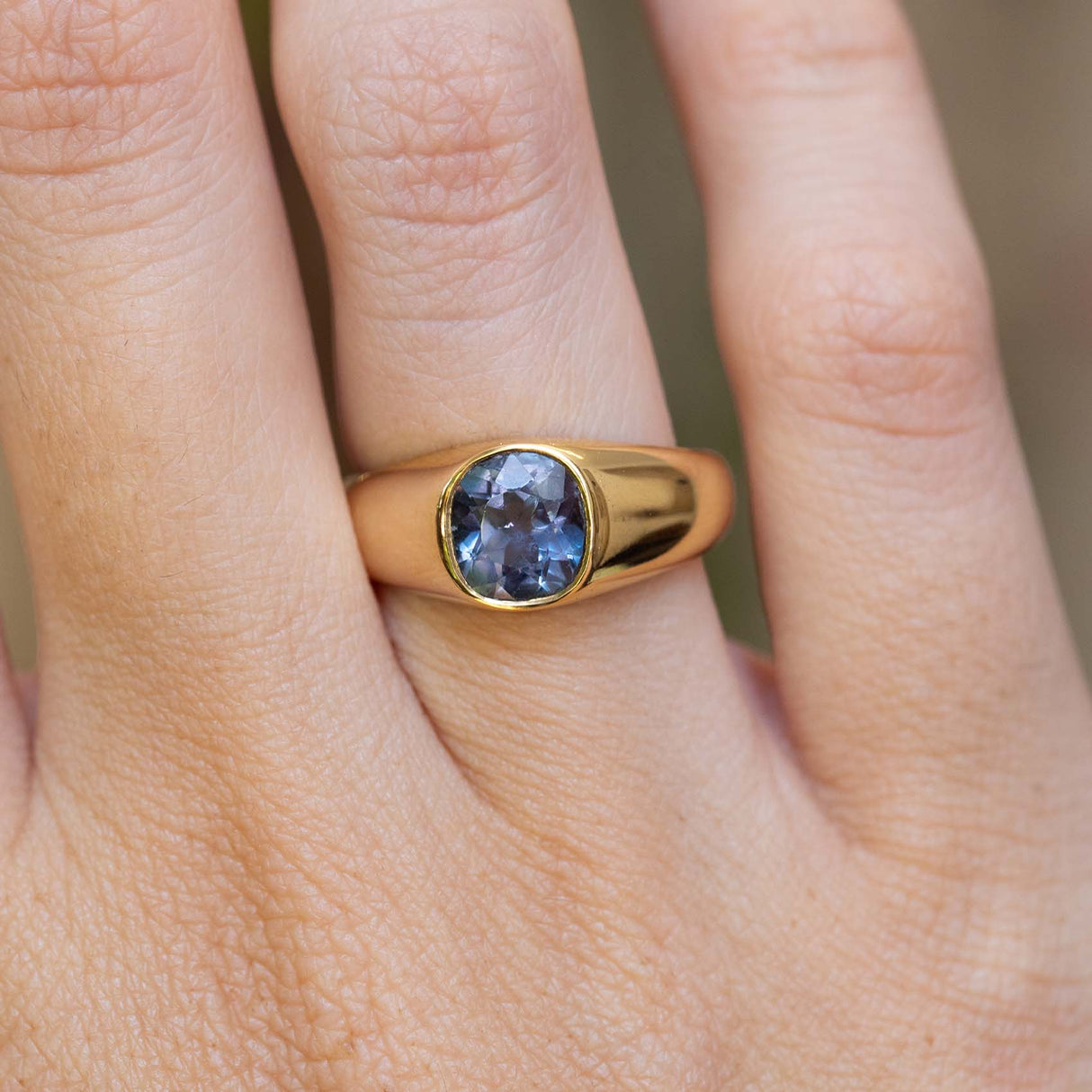 An antique Victorian colour-change blue sapphire gypsy ring worn on the finger.