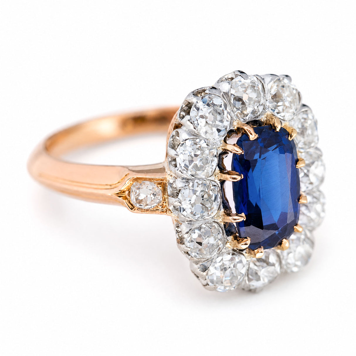A three-quarter of an antique, Jugendstil Royal-blue sapphire and diamond cluster ring with a rose gold band.