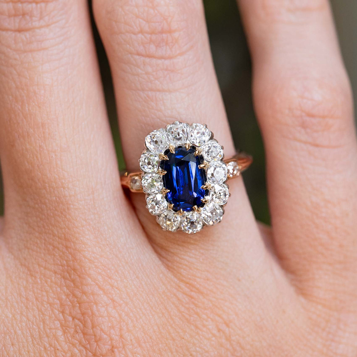 An antique Jugendstil royal-blue sapphire and diamond cluster ring worn on the finger.
