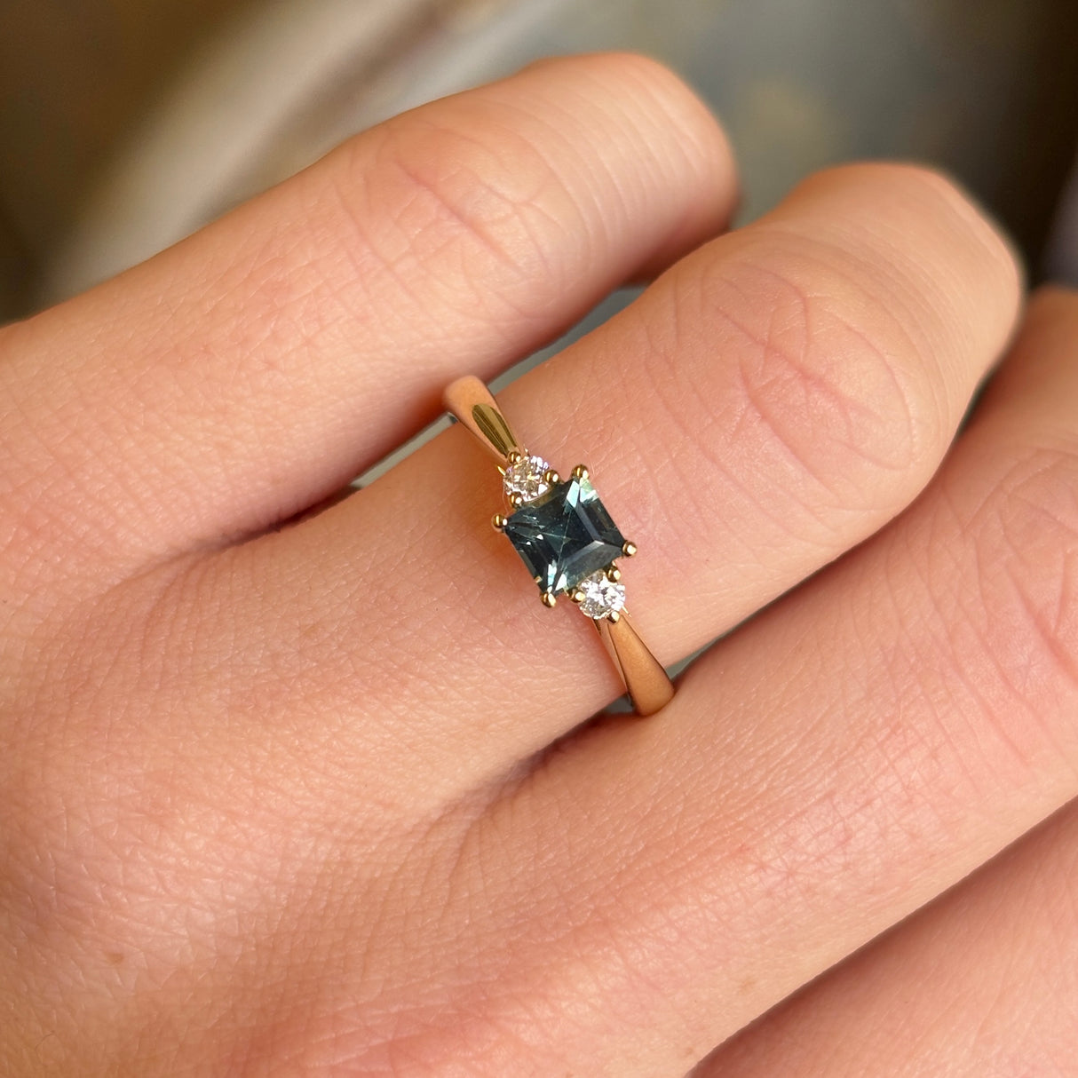 Square-cut teal sapphire and diamond three-stone engagement ring