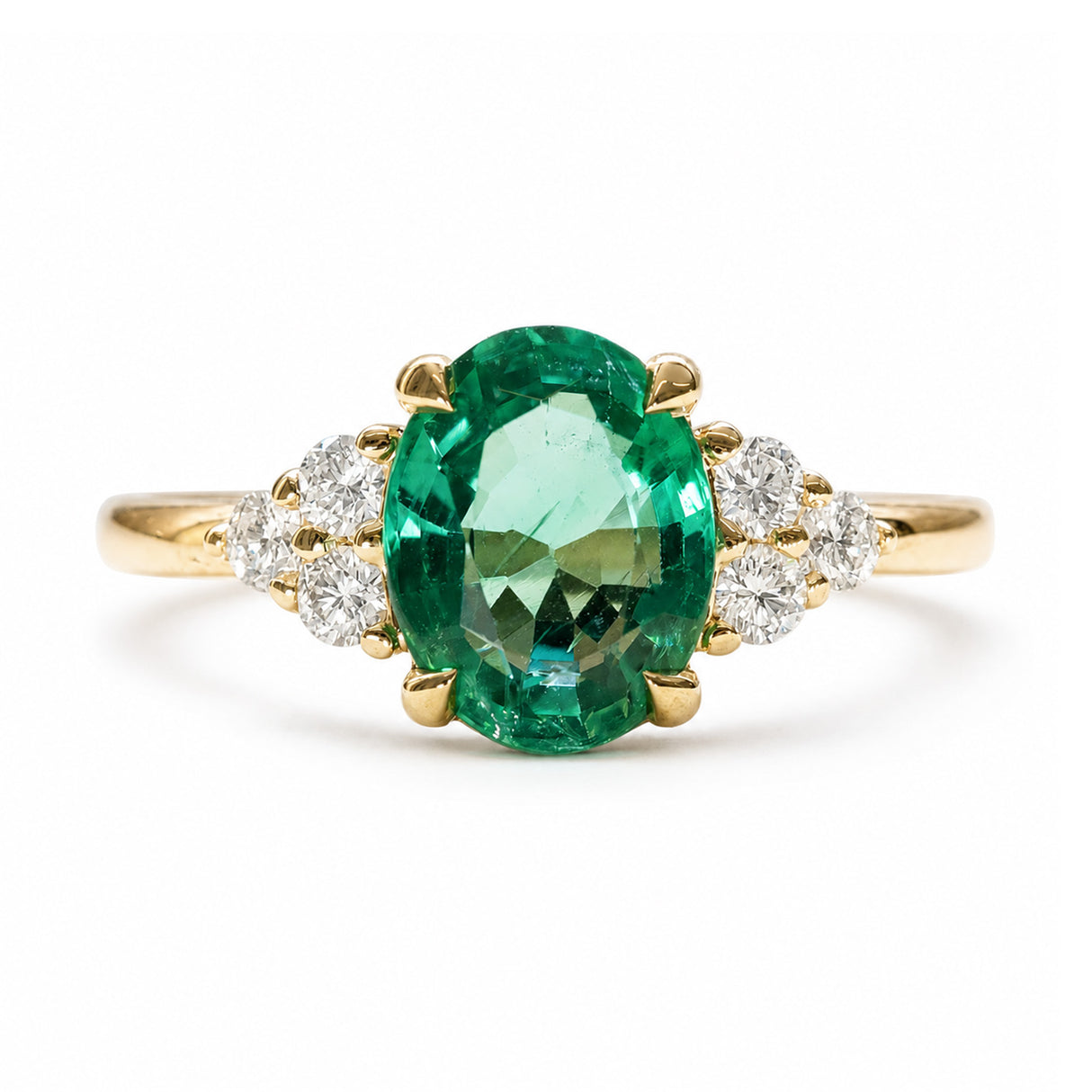 A vintage-inspired, oval-cut emerald and diamond cluster tre-foil engagement ring in yellow gold.