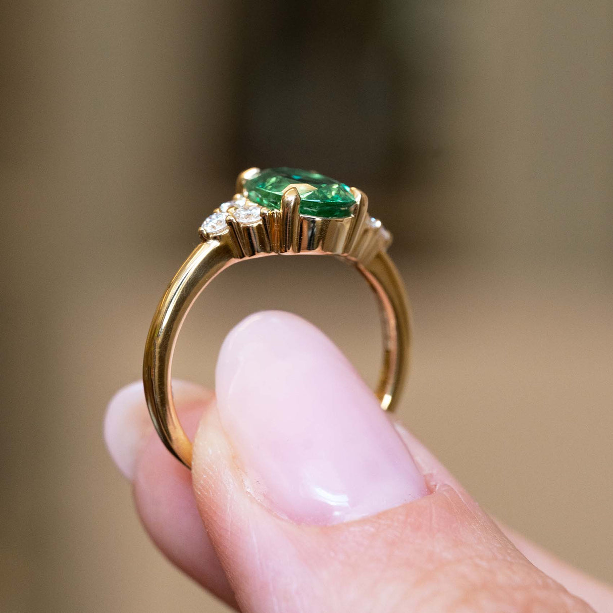 Gallery detail of a vintage-inspired oval-cut emerald and diamond trefoil engagement ring in yellow gold.