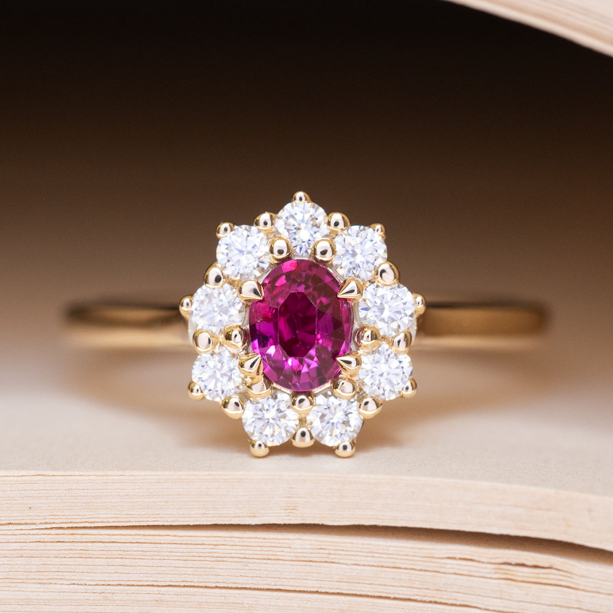 An antique-inspired pink ruby and diamond cluster engagement ring in yellow gold.