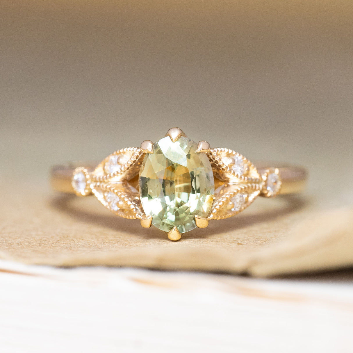 A vintage-inspired, green sapphire & diamond engagement ring in yellow gold.