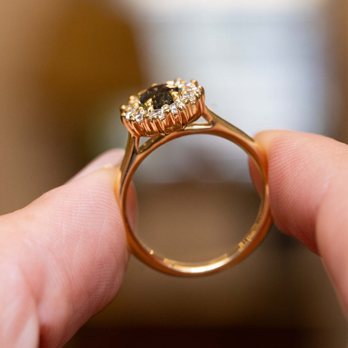 Side detail of an antique-inspired green sapphire and diamond cluster engagement ring crafted in yellow gold.