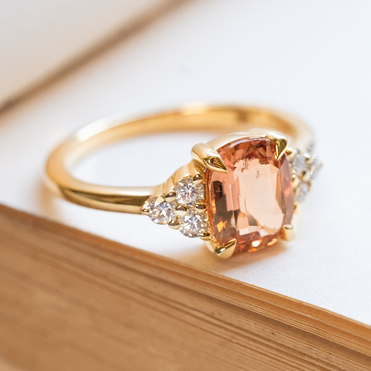 A vintage-inspired, Apricot-orange sapphire & diamond cluster trefoil engagement ring in yellow gold.