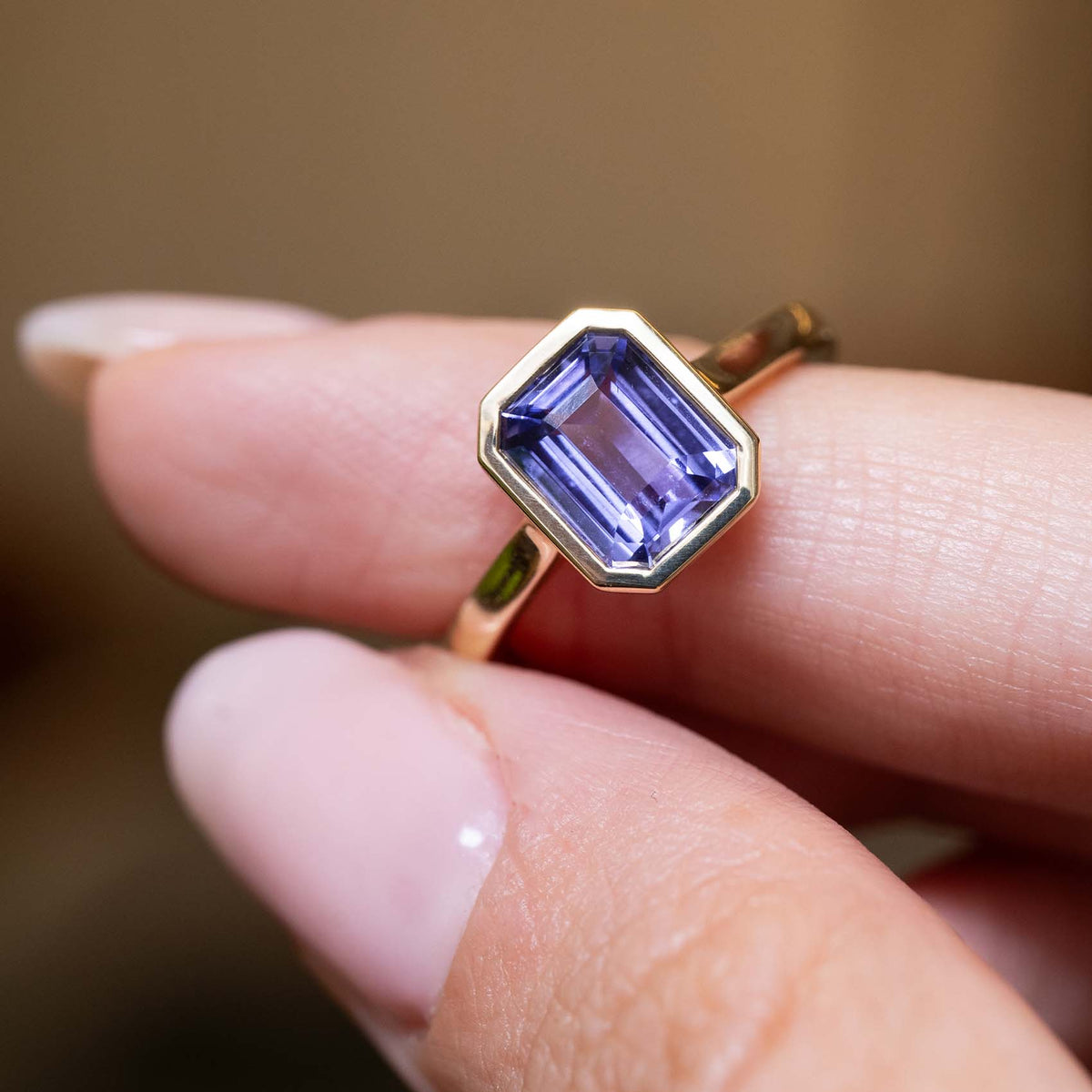 Close-up of an antique-inspired indigo blue sapphire solitaire ring with a yellow gold bezel setting.