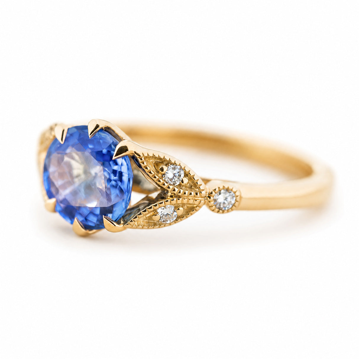 A three-quarter angle of a yellow gold engagement ring with a round blue sapphire with diamond details in the shoulders.