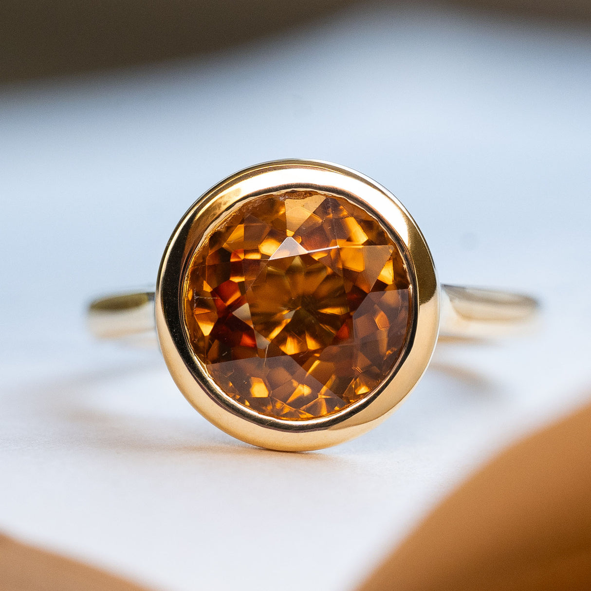 An antique-inspired, deep orange zircon solitaire ring in yellow gold.