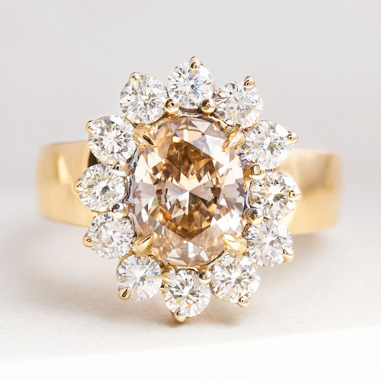Vintage 1980s fancy coloured brown diamond cluster ring featuring an oval brown diamond surrounded by a sparkling cluster of brilliant-cut white diamonds in yellow gold.