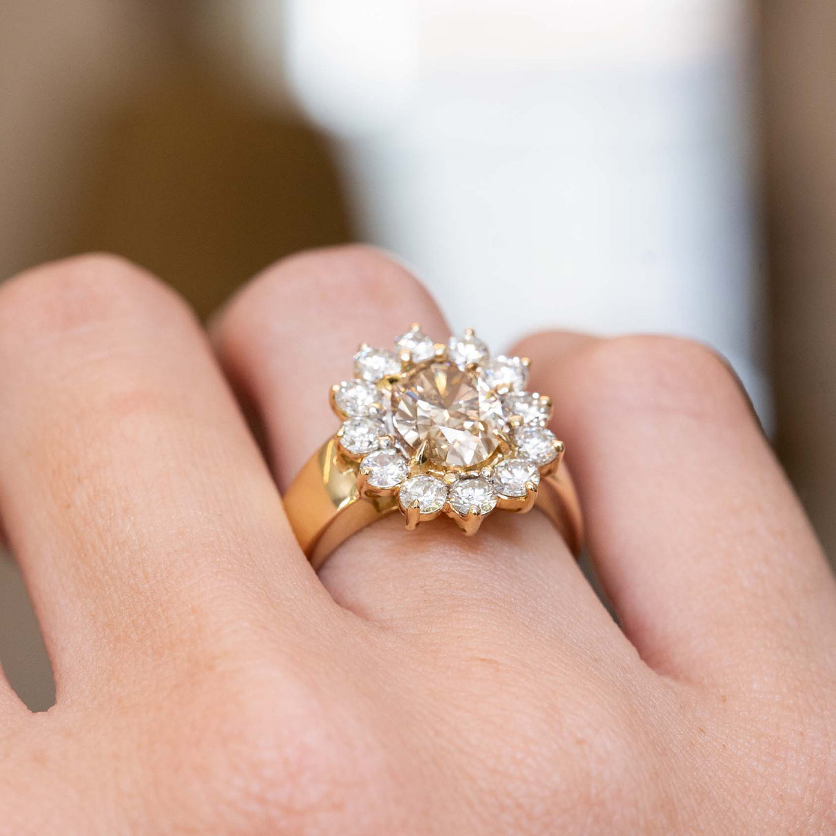 Detailed view of a vintage 1980s brown diamond cocktail ring worn on the hand, featuring an oval fancy coloured brown diamond and diamond cluster surround.