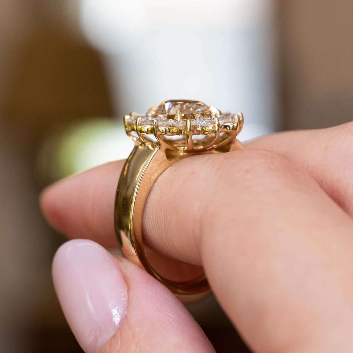 Detailed view of a vintage brown diamond cocktail ring showing its side view of the setting, resting on a finger.
