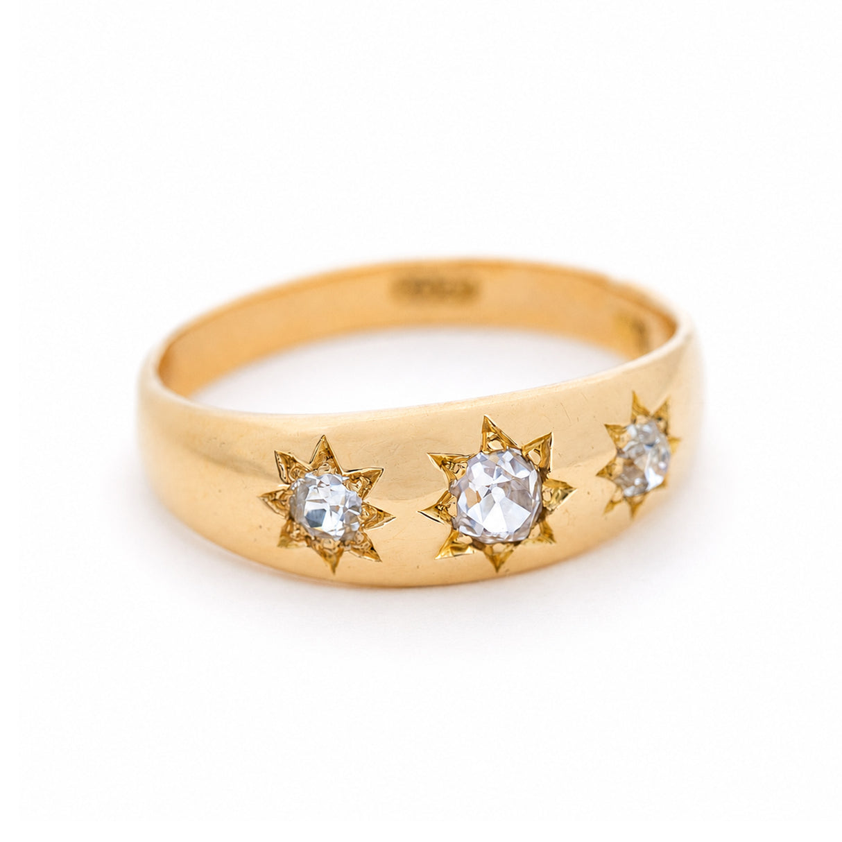 A three-quarter angle of an antique, Edwardian diamond three-stone gypsy ring in yellow gold.
