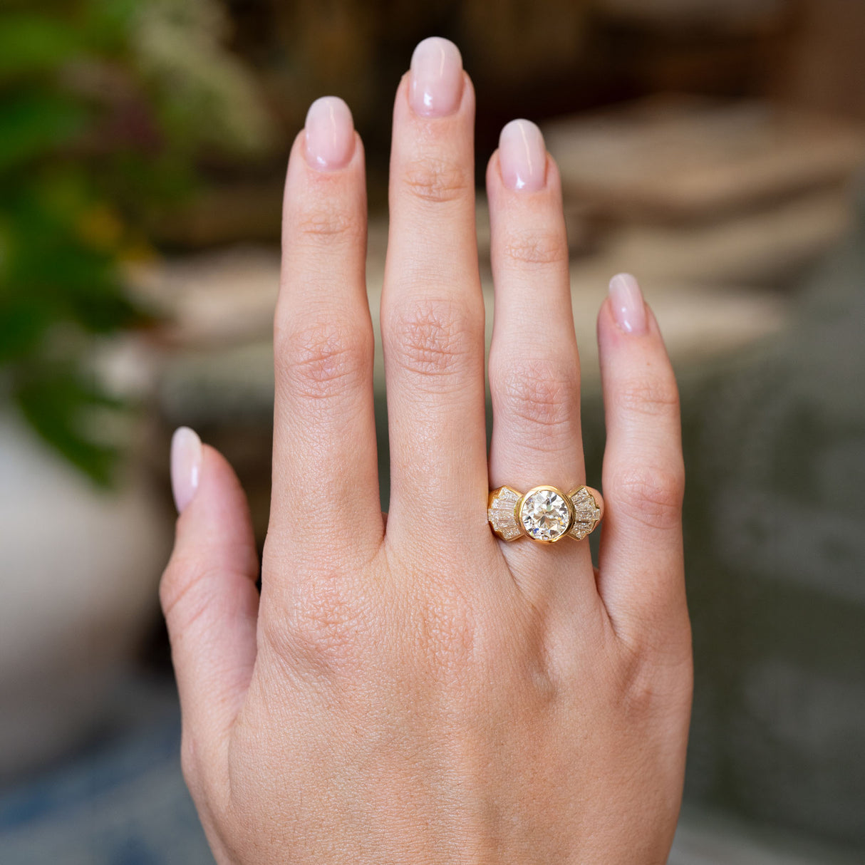Vintage 1950s old-cut diamond fan engagement ring worn on the hand, featuring a bezel-set old-cut diamond with tapered baguette diamond fan shoulders.
