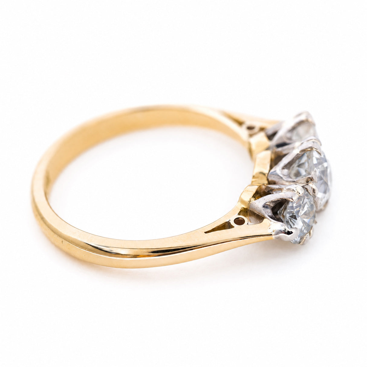 An angled view showing the gallery and yellow gold band of a diamond three-stone ring.