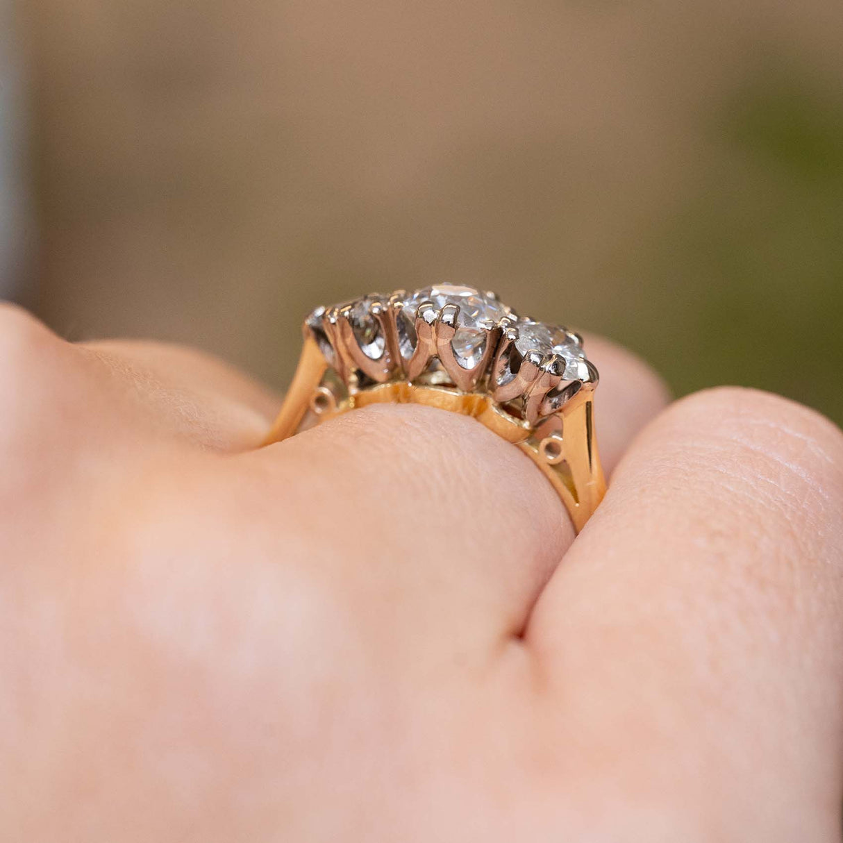 A side profile of the raised three-stone diamond setting worn on the finger.