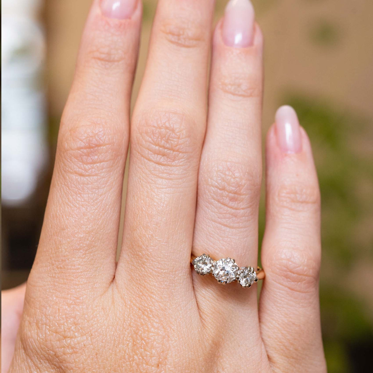 1960s old-cut diamond engagement ring shown at full scale on the hand against a blurry background.