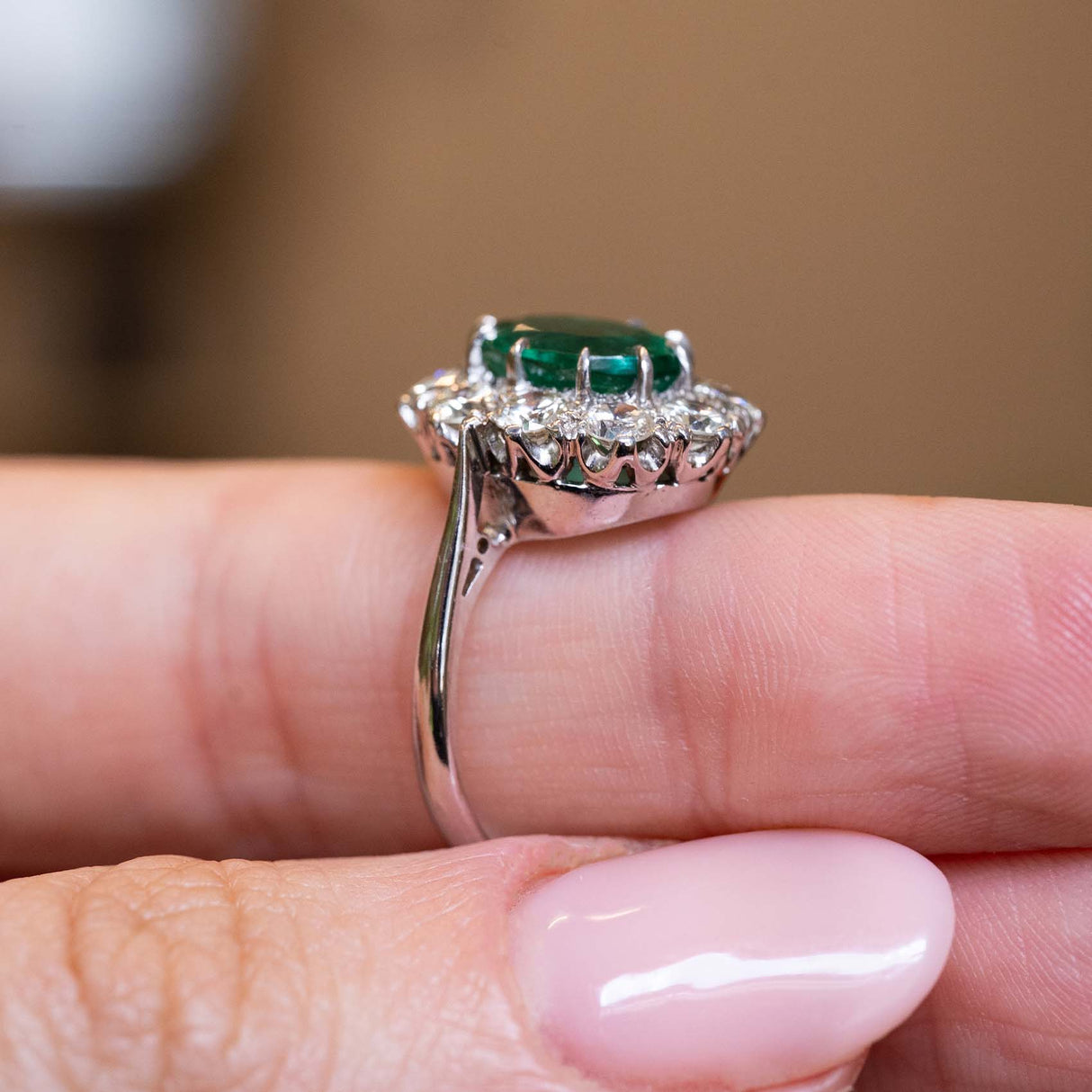 Side detail of a vintage 1950s oval-cut emerald and diamond cluster engagement ring in white gold.