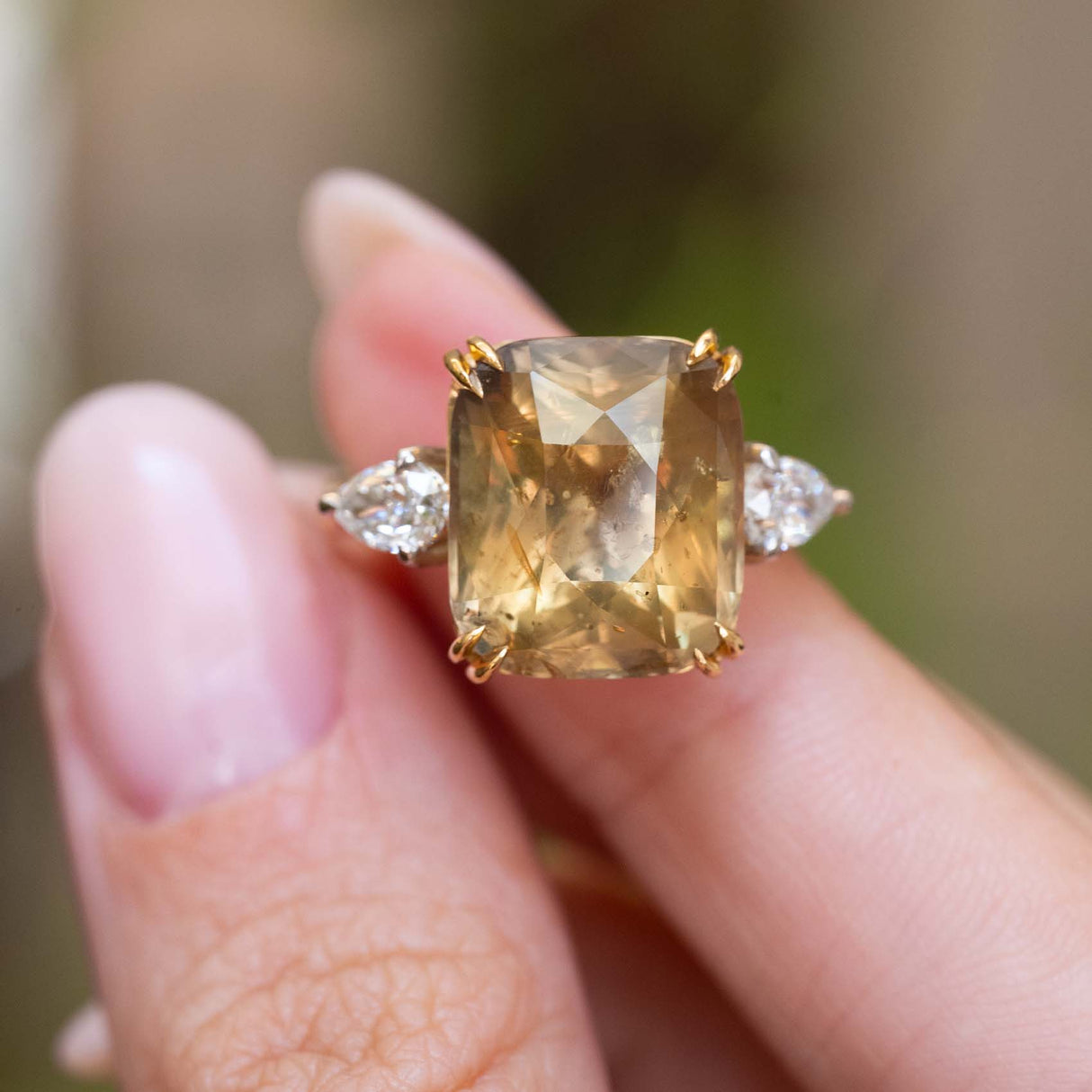 Close-up of a large cushion-cut brown sapphire with pear-shaped diamonds