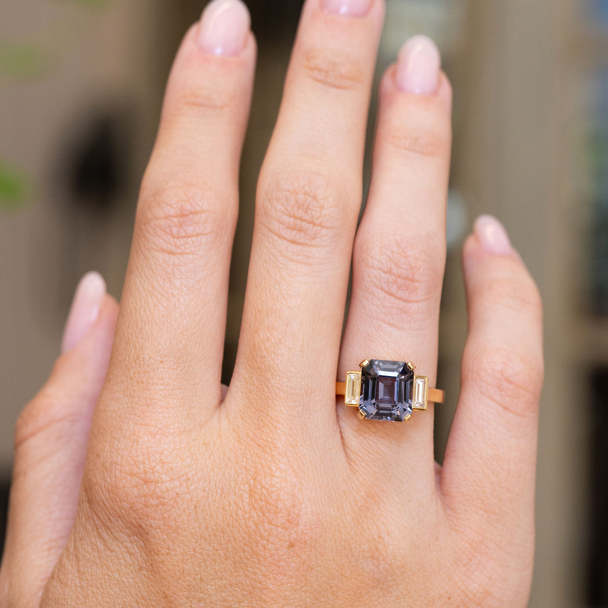 Blue spinel three-stone engagement ring shown at full scale on the hand