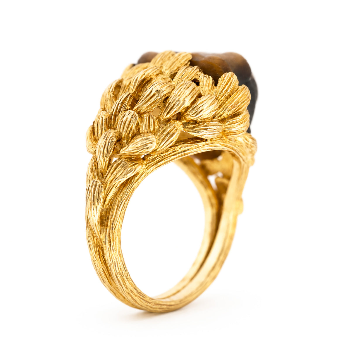 A photo of the side of a Vintage, 1980's French tiger's eye honey bear ring in carved yellow gold on a plain white background