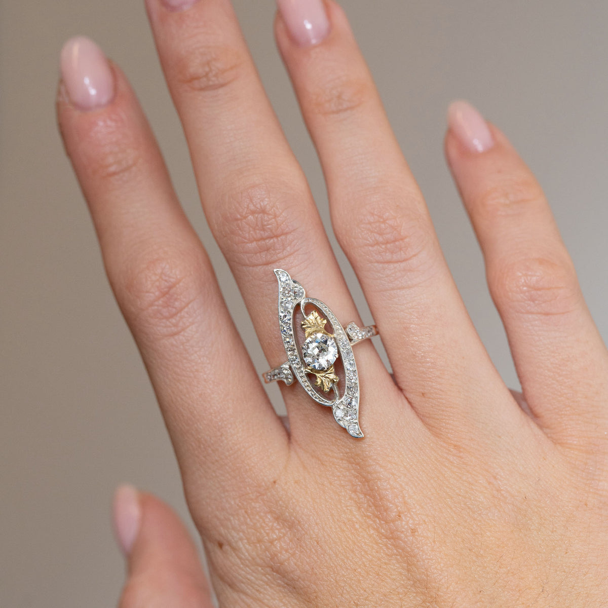 Antique Art Nouveau diamond cross-over ring worn on the finger, showcasing its elongated, flowing diamond-set design.