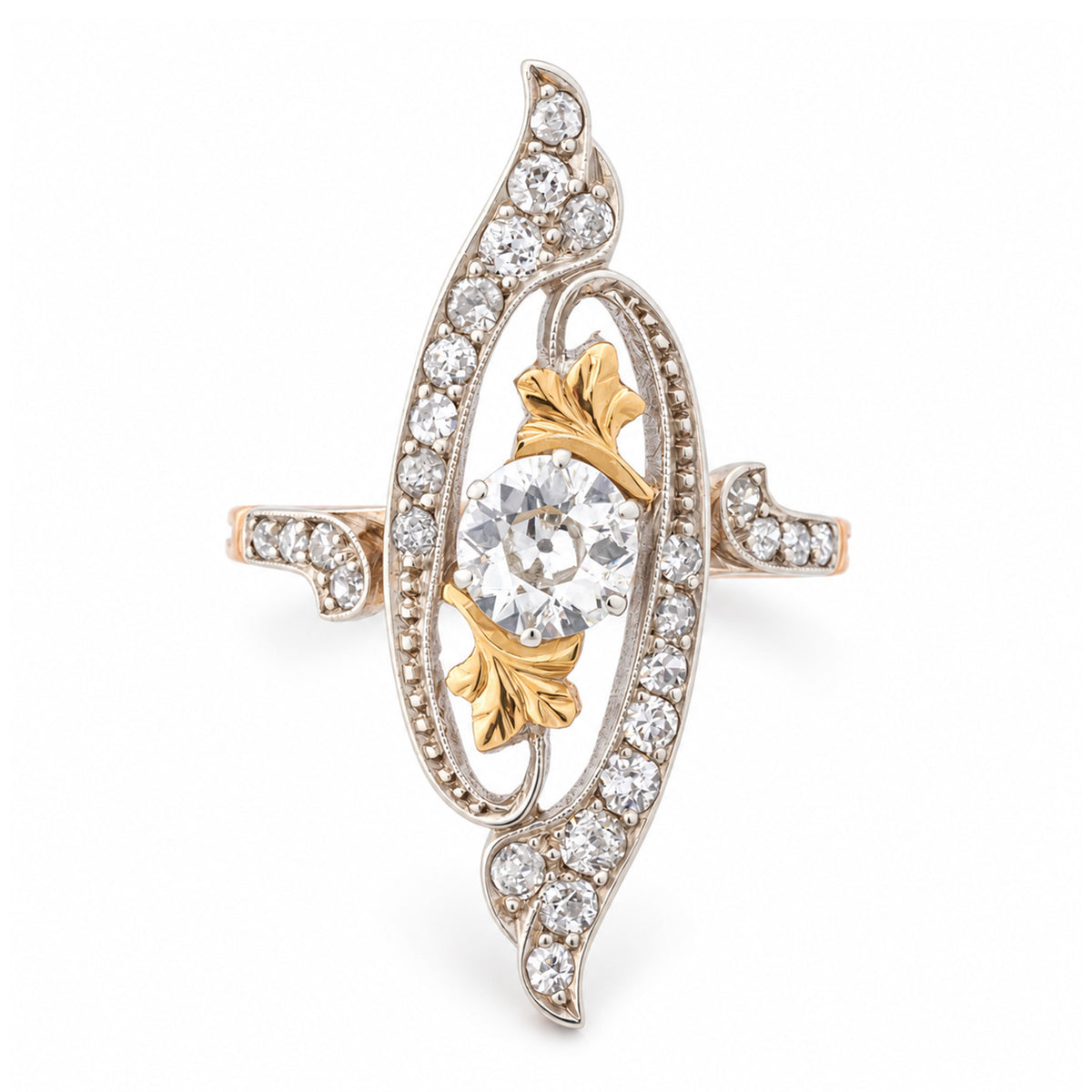 Antique Art Nouveau diamond cross-over ring in yellow gold and platinum, featuring an old-cut diamond within an ornate diamond-set swirling design.