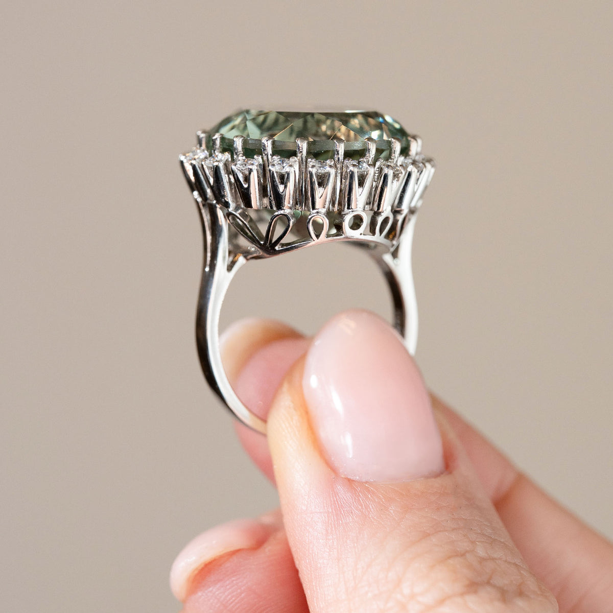Profile photograph of the vintage white gold cluster ring, showing its ornate openwork gallery and elevated gemstone setting.