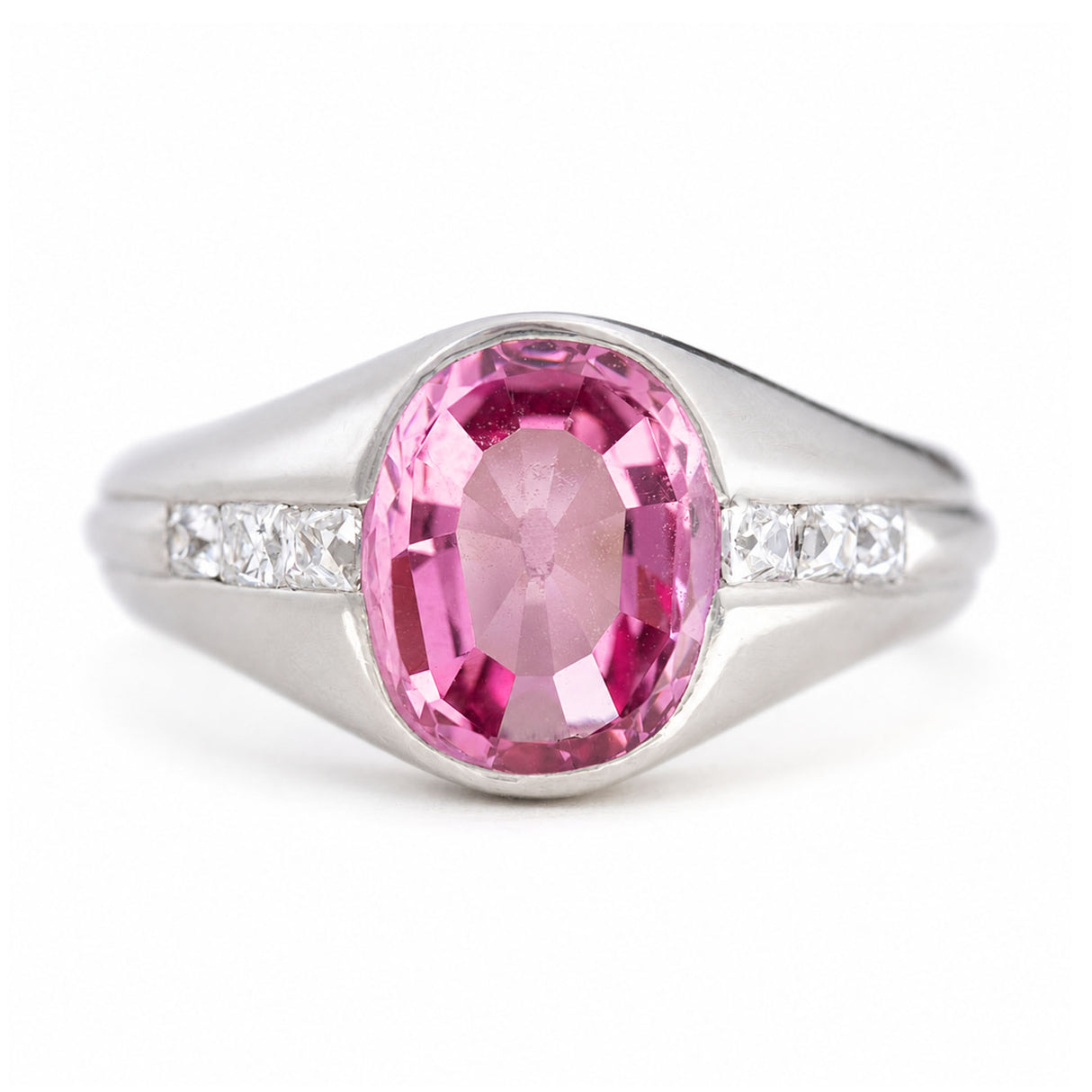 A vintage, 1940s pink sapphire and diamond gypsy ring in platinum on a white background