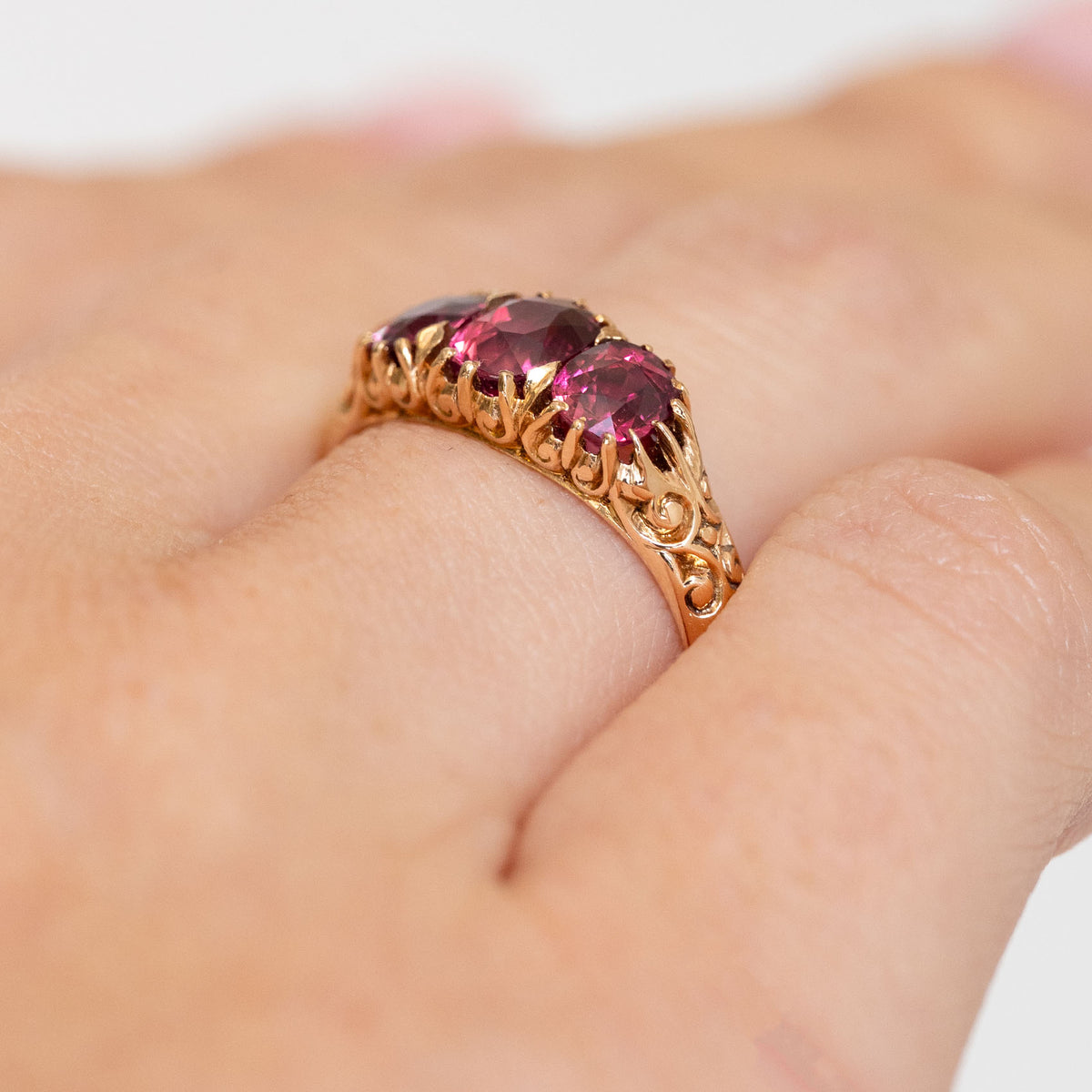 Side angle revealing the raised ruby settings, pierced gold shoulders and intricate carved motifs.