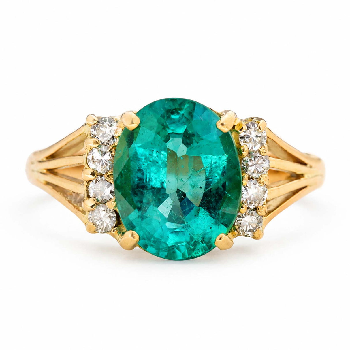 A yellow gold Vintage, 1970s emerald and diamond engagement ring featuring a large central oval-cut emerald, accented by small clear round diamonds on each side of the band, set against a plain white background.